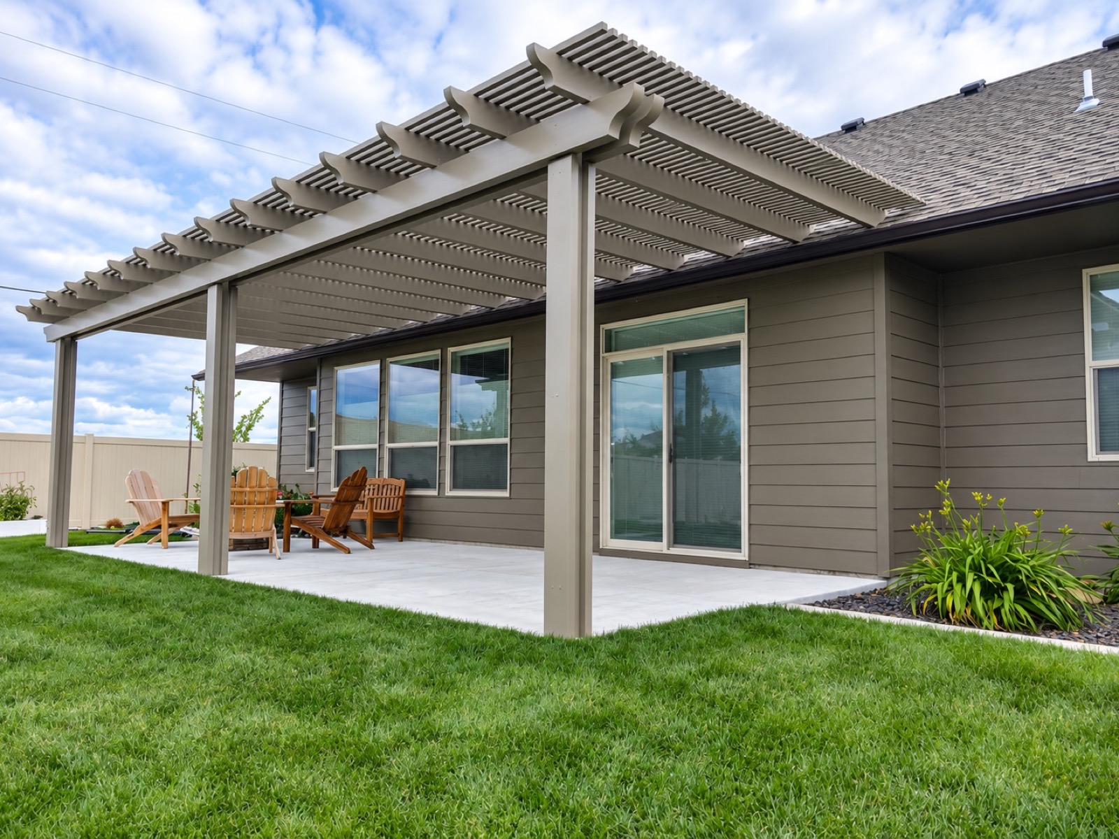 Tan aluminum pergola attached to a Utah home over a backyard patio, built by Blackrock Decks