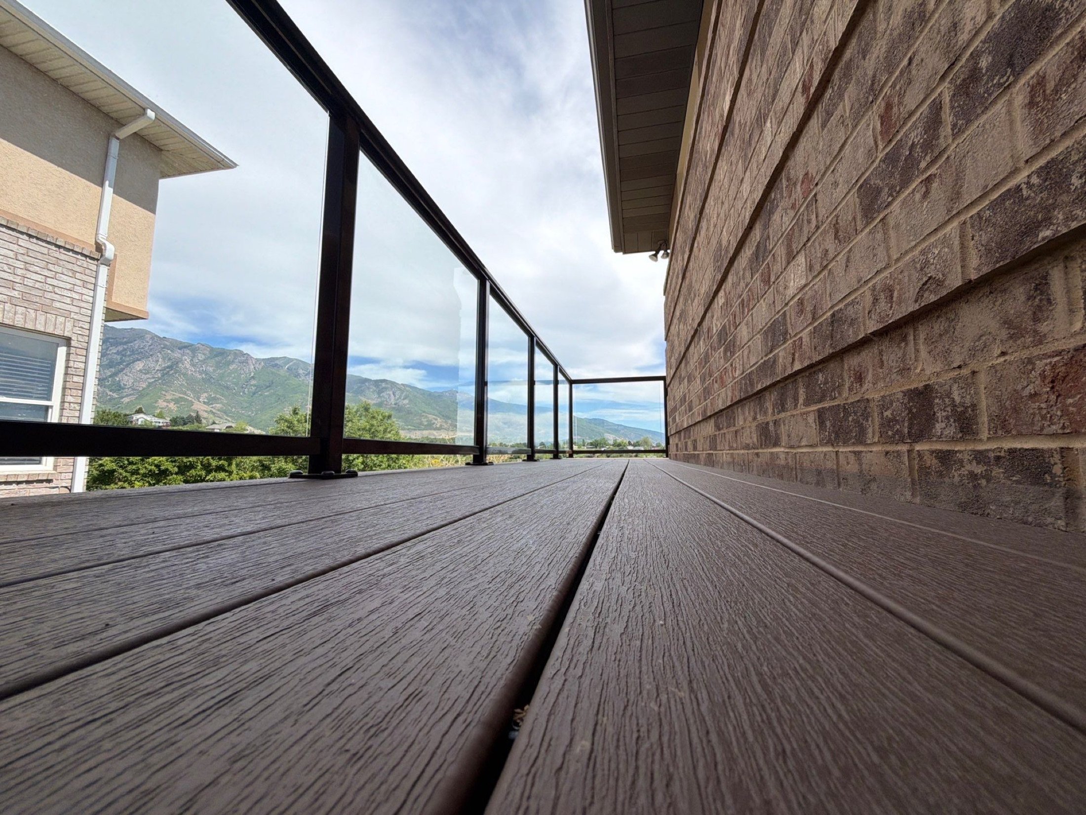 Composite deck boards running out to a glass railing with the Wasatch mountains beyond