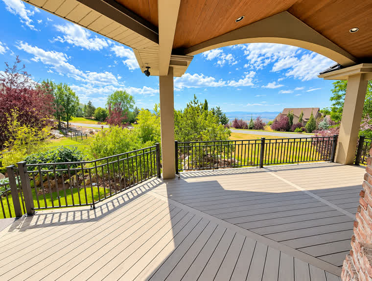 Covered deck under an arched roof line with diagonal Trex boards and black railing