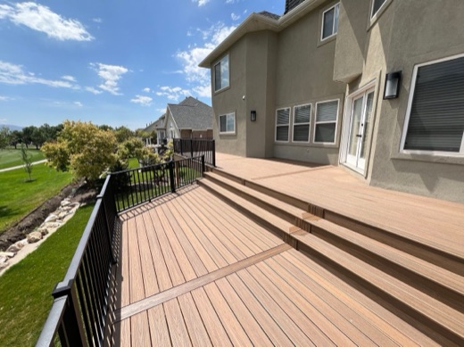 Wide tan composite deck with black picket railing and golf course views