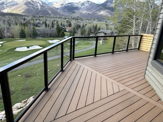 Composite deck with black glass railing overlooking a golf course and the mountains