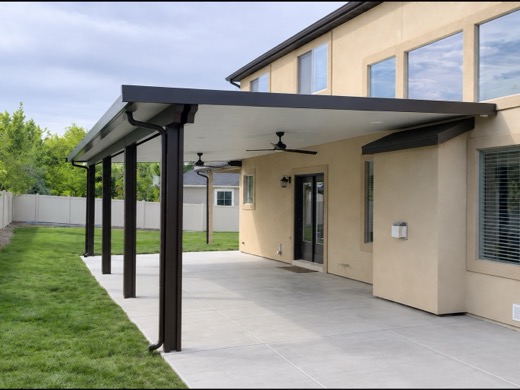 Black flat-roof aluminum patio cover with ceiling fans on a stucco home