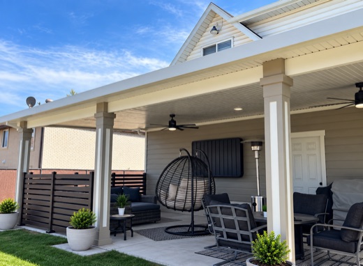 White attached patio cover with ceiling fans over a concrete patio
