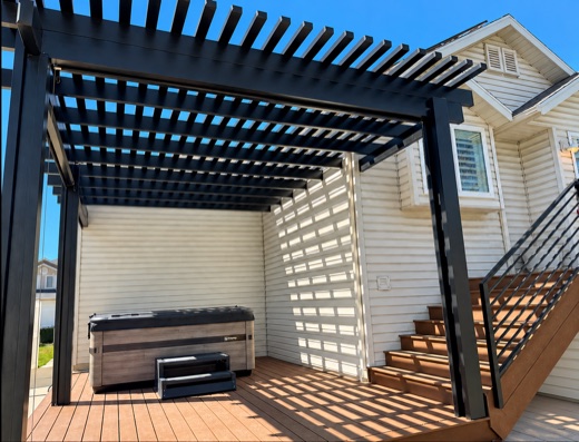 Black louvered pergola over a composite deck with a hot tub