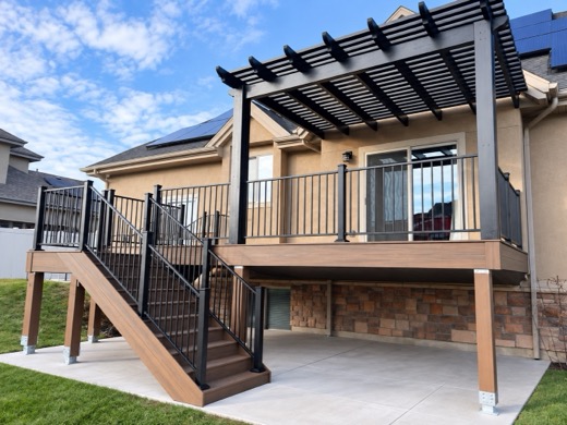 Black aluminum pergola over an elevated composite deck with stairs