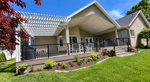 White attached pergola over a brown composite deck with cable railing