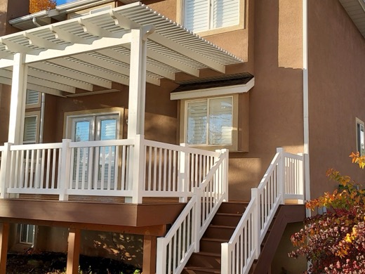 White aluminum pergola over a deck on a stucco home