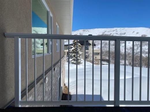 White aluminum picket railing on balcony overlooking snowy yard and hillside