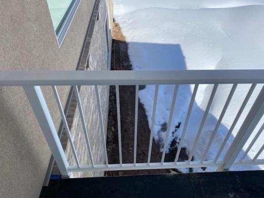 White aluminum picket railing on small landing beside stucco wall with snowy yard