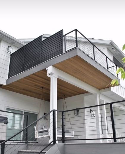Black cable railing on a two-story deck of a white farmhouse-style home