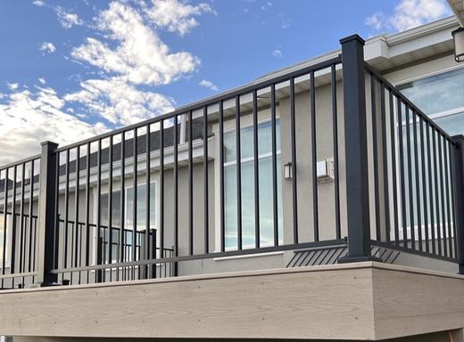 Black aluminum picket railing on raised deck with light composite fascia and blue sky (Cinch railing)