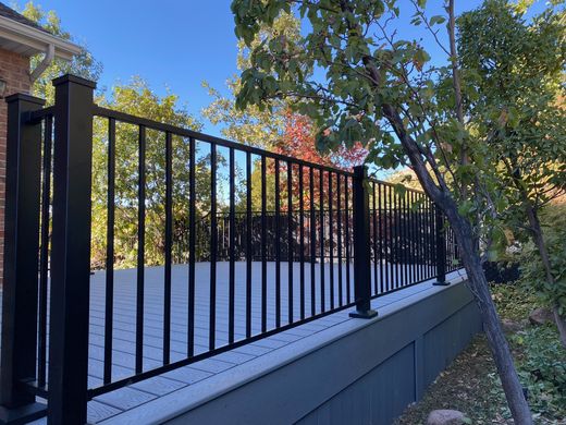 Black Cinch steel picket railing on a gray composite deck in fall