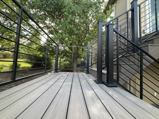 Black horizontal-rod railing with a matching gate around a gray composite deck