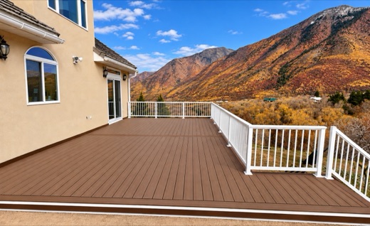 Brown composite deck with white picket railing looking out at autumn mountains