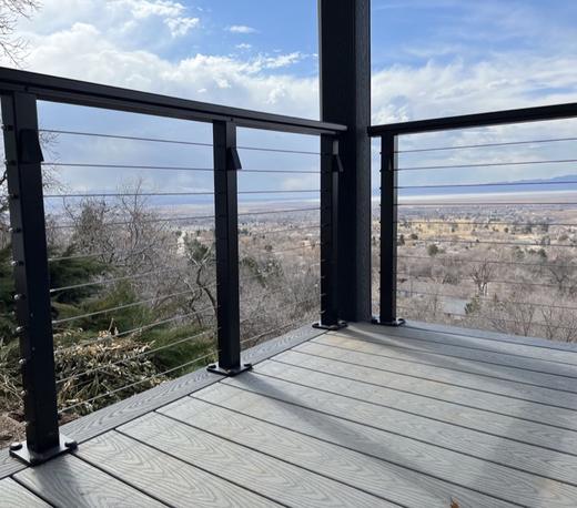 Black cable railing on gray composite deck overlooking valley and distant mountains (Precision railing)