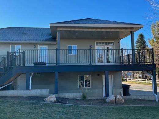 Raised deck with black metal picket railing, stairs to yard, partly covered roof (Cinch railing)