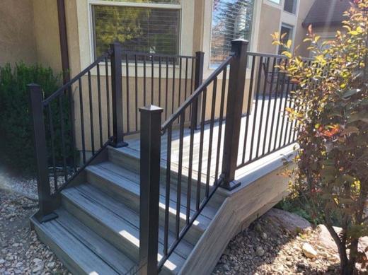 Black metal picket railing on gray composite entry deck with wide stairs (Cinch railing)