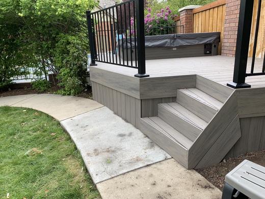 Gray composite deck with black picket railing and wide stairs to concrete walkway (Cinch railing)