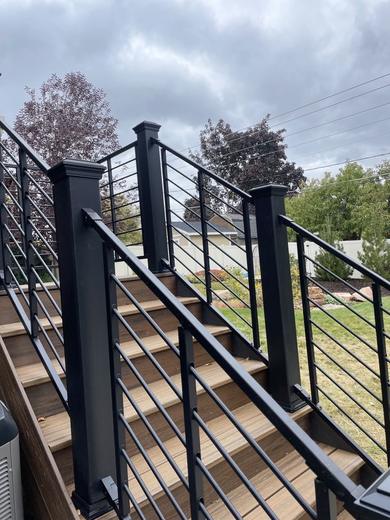 Black horizontal rod railing along composite deck stairs under cloudy sky (Trex Transcend)