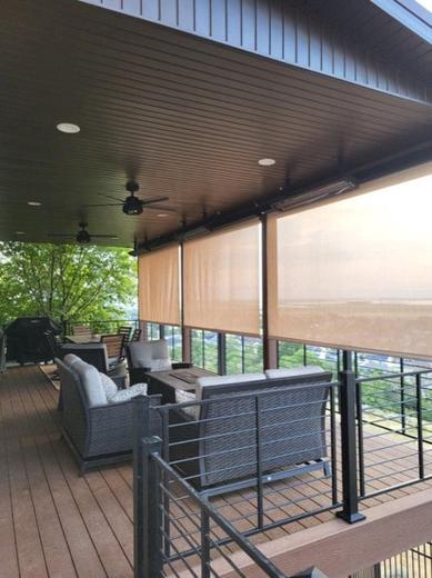 Covered deck with black cable railing, wood ceiling, fans, shades and wicker seating