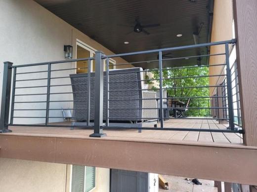 Black horizontal rod railing on covered second story deck with brown composite flooring