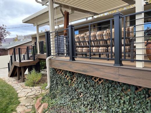 Black horizontal rod railing on brown composite deck under white pergola cover with stairs (Trex Transcend)