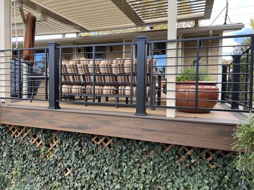 Black horizontal rod railing with square posts on brown deck under covered patio (Trex Transcend)