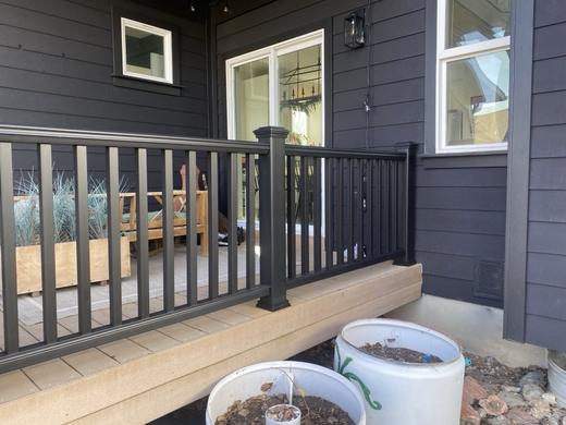 Black metal picket railing along a low porch on a dark sided house