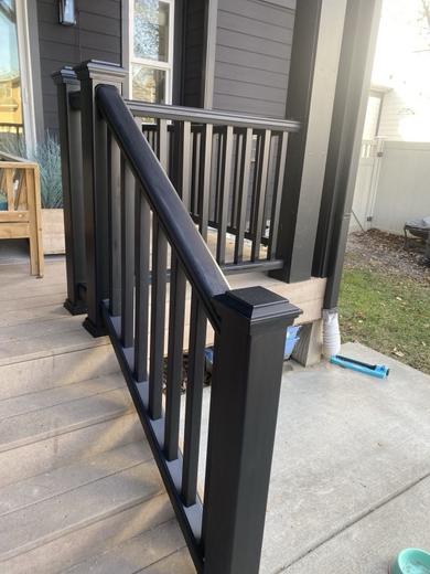 Black composite railing with vertical pickets along covered porch steps and gray decking