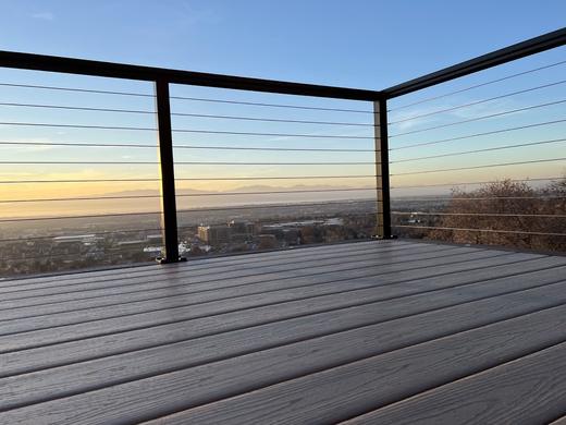 Black cable railing on gray composite deck overlooking valley and distant mountains at sunset (Precision railing)