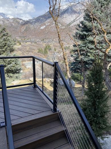 Black cable railing on brown composite deck and stairs with mountain view (Precision railing)