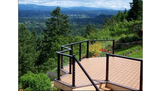 Cable railing with black posts on hillside deck with stairs overlooking forested valley (Precision railing)