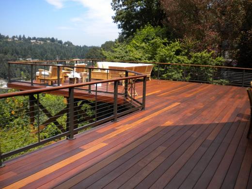 Hardwood deck with horizontal cable railing, wood top rail, overlooking green treed hillside (Precision railing)