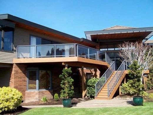 Raised deck with glass panel railing and wood stairs with dark metal pickets (Precision railing)