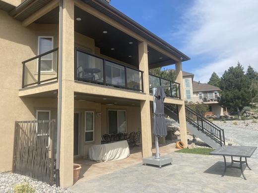 Upper deck with black framed glass railing, covered patio below and stair railing (Precision railing)