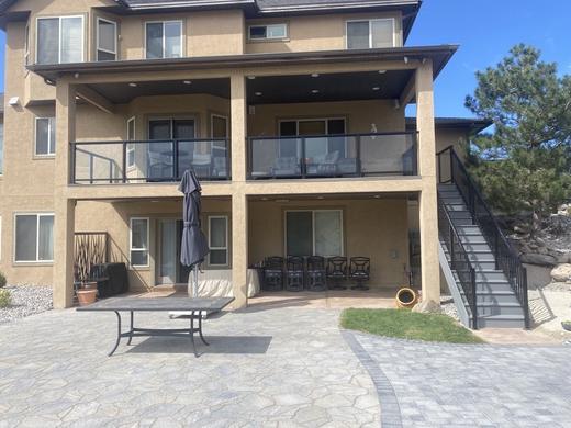 Covered second-story deck with black posts and glass panel railing, black metal stairs (Precision railing)