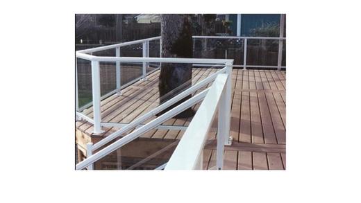 White framed glass panel railing wrapping a wood deck around a tree (Precision railing)