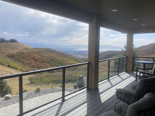 Covered deck with black-framed glass railing, gray composite floor, wide mountain valley view