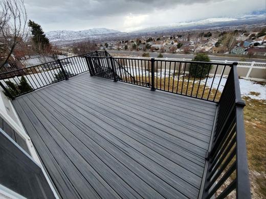 Gray composite deck with black metal picket railing overlooking snowy valley and mountains (Trex Signature)