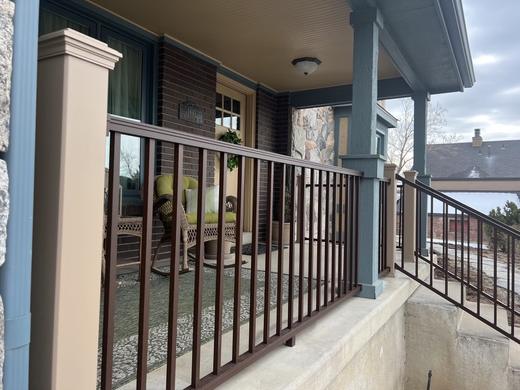 Bronze metal picket railing along covered brick front porch with stair run (Trex Signature in Rope Swing)