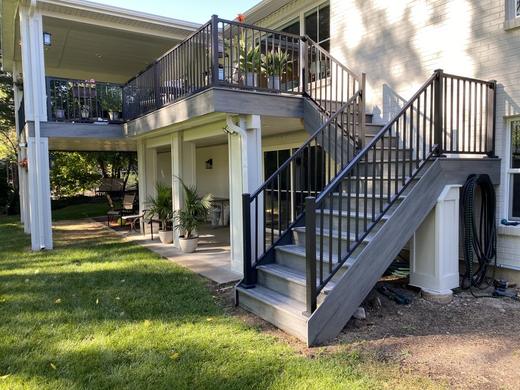 Raised gray deck with black metal picket railing and stairs over covered patio (Trex Signature)