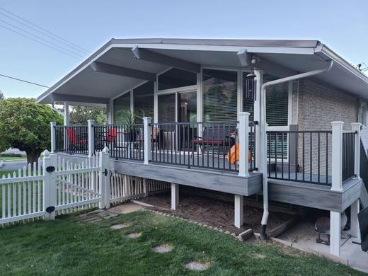 Covered porch with white posts and black metal pickets beside white picket fence (Trex Transcend)