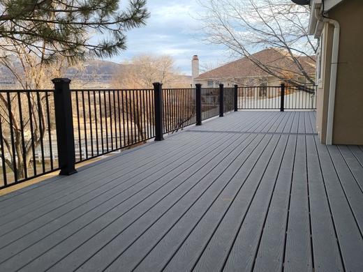Gray composite deck with black metal picket railing and distant hillside views (Trex Transcend)