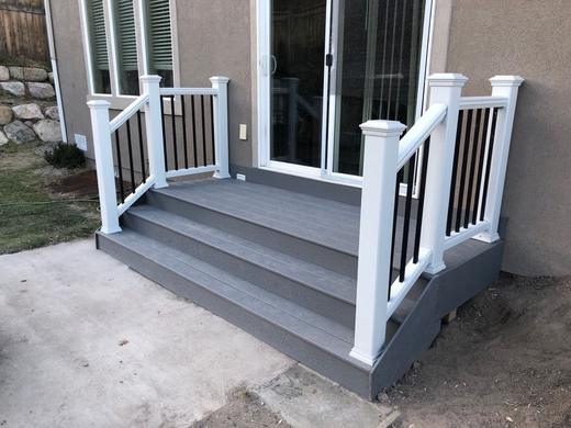 Small gray composite landing with wide steps, white posts and black metal balusters (Trex Transcend)