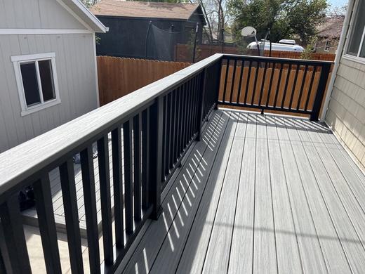Gray composite deck with black metal pickets and light composite top rail in backyard (Trex Transcend in Island Mist)