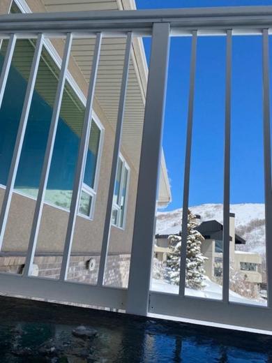 White vertical picket railing on deck with snowy hillside and homes beyond