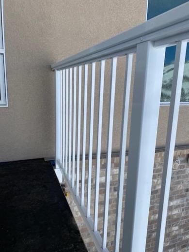 White aluminum picket railing along balcony beside stucco wall and brick exterior