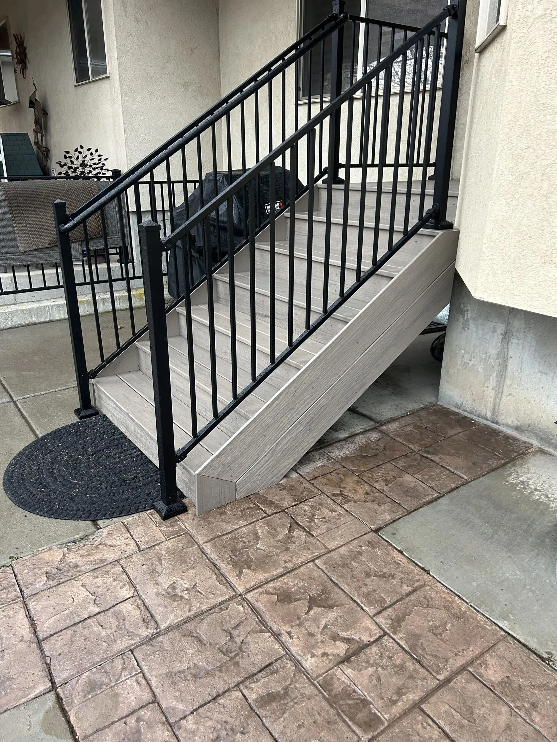 IMG_4235 A covered patio with a black metal railing and decorative flooring tiles