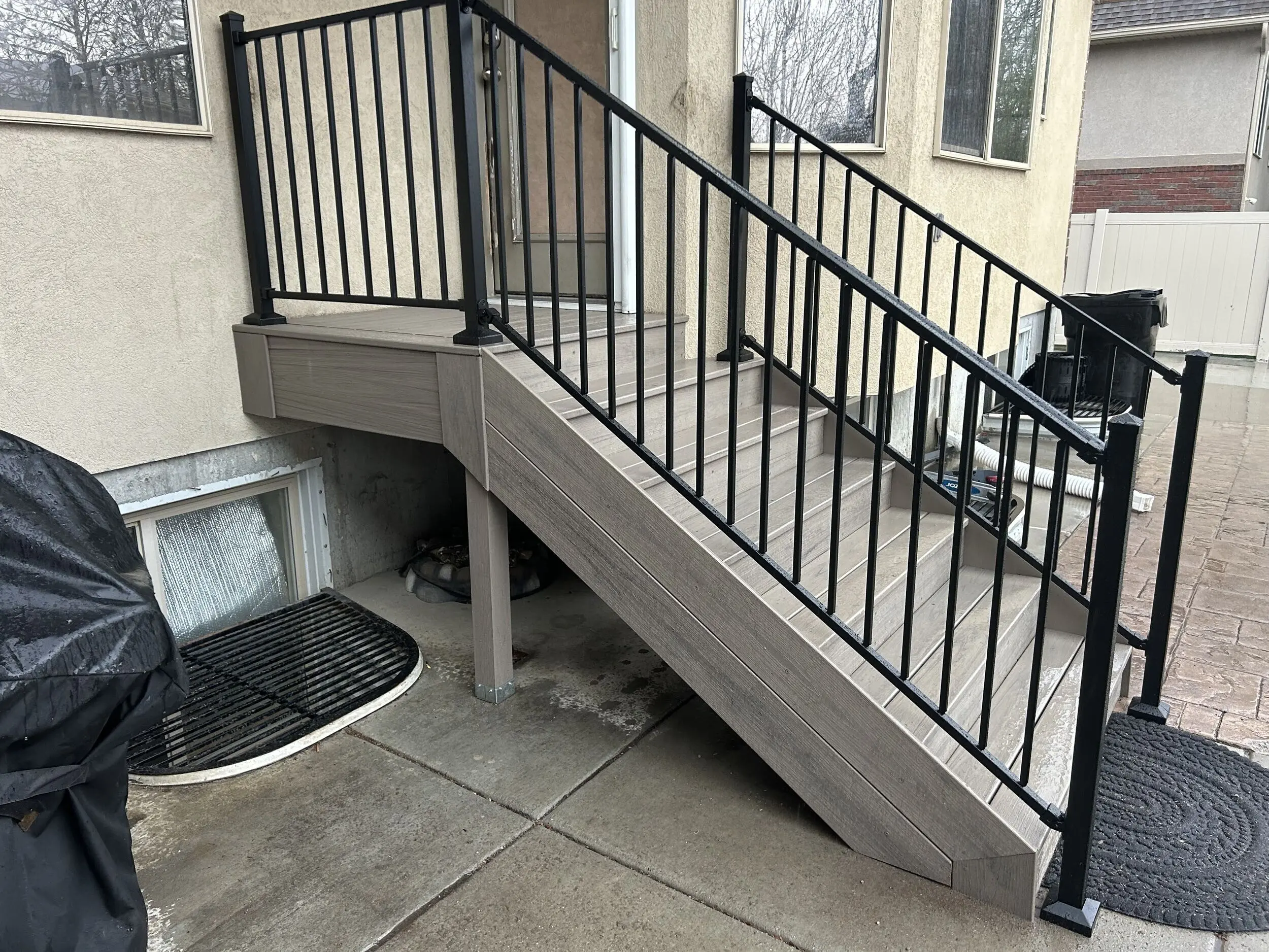 IMG_4238 A set of concrete steps leading up to a covered porch or entryway. The steps have a black metal railing on both sides.