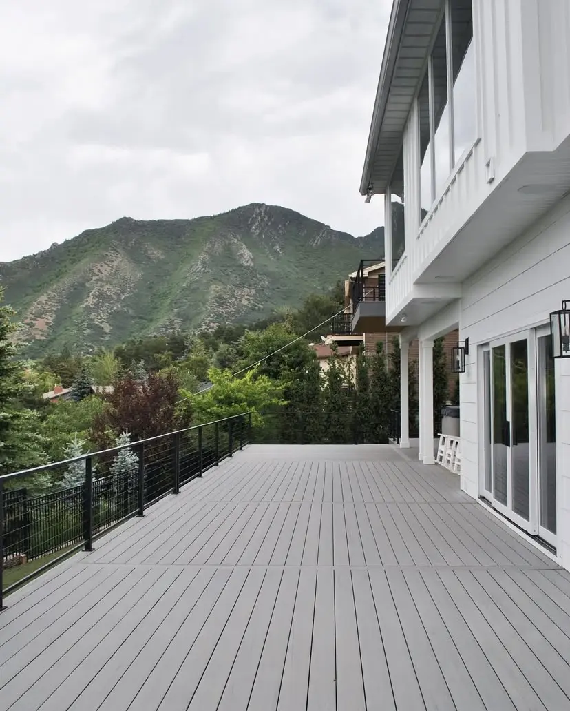 A wide deck with a metal railing overlooking a mountainous, forested area.